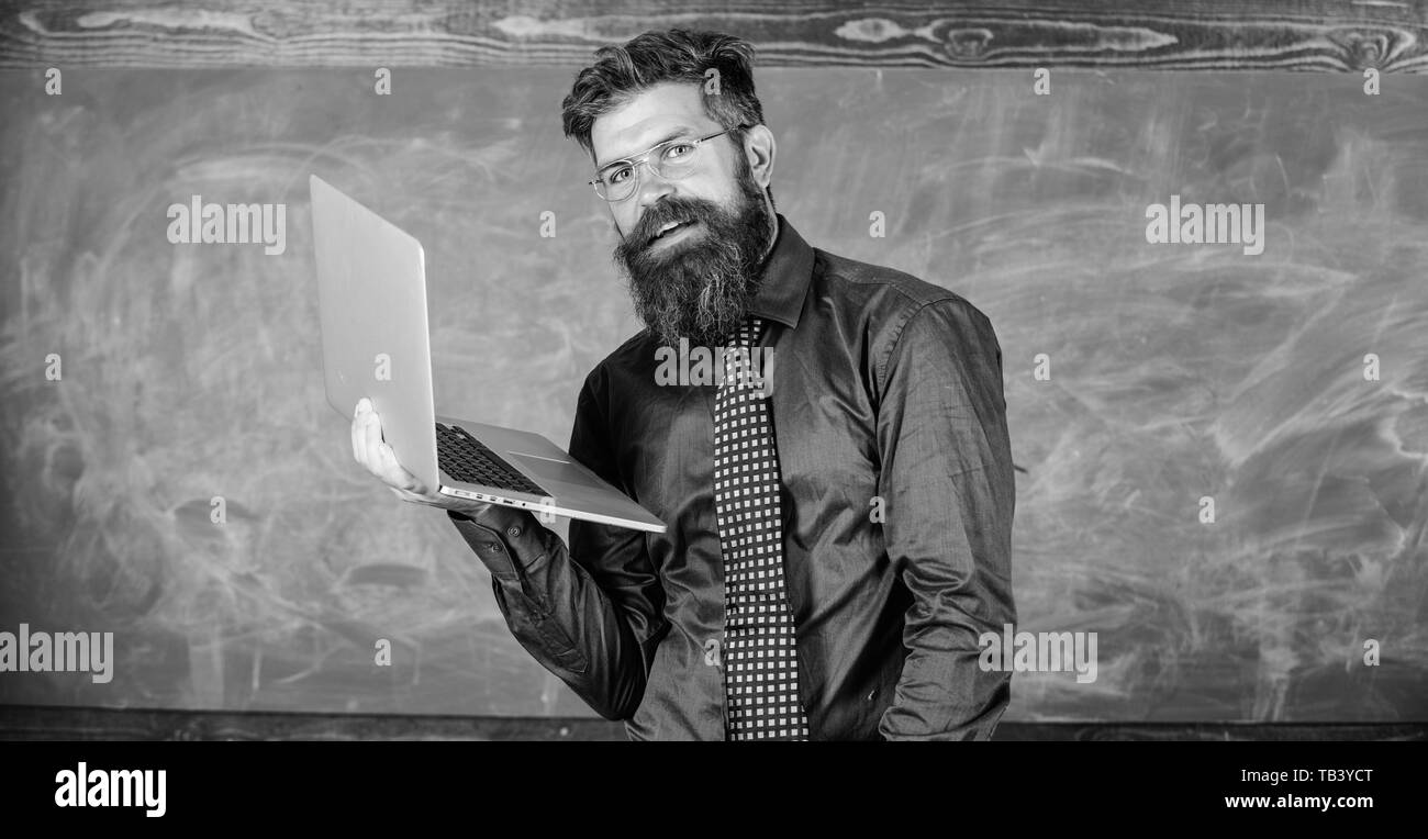 Professeur Hipster portent des lunettes et cravate est titulaire d'ordinateur portable Internet surf. Concept de formation à distance. Homme barbu enseignant avec ordinateur portable moderne tableau internet surf arrière-plan. Surfer sur internet. Banque D'Images