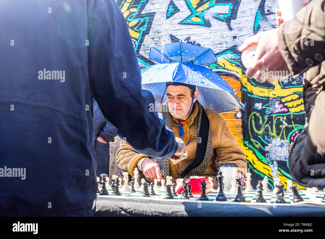 Shoreditch, London, England, UK - Avril 2019 : old man street joueur jouant aux échecs avec un parapluie comme hat dans Brick Lane, East London Banque D'Images