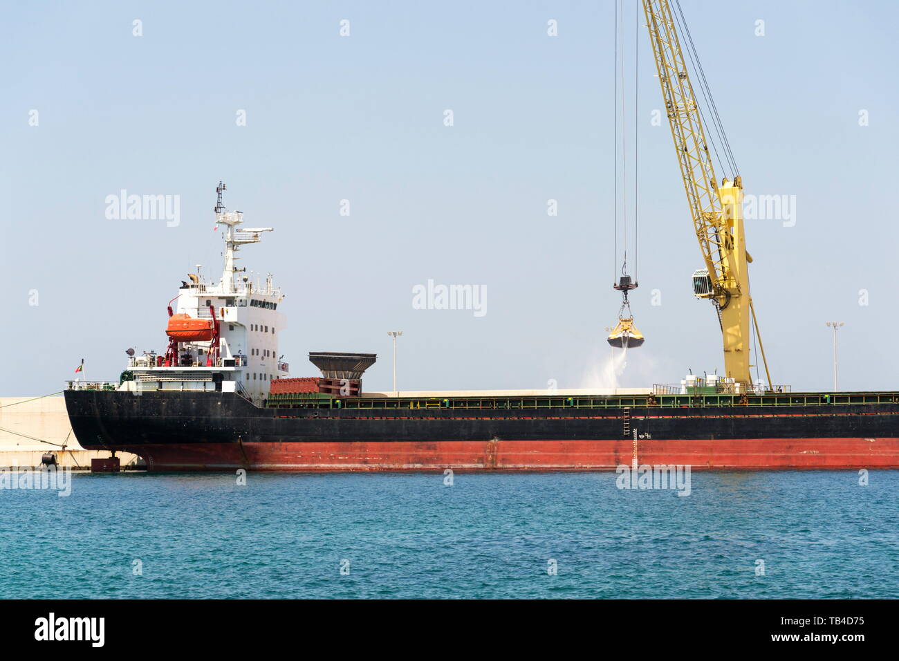 Grue de déchargement de sable jaune grand cargo cargo dans le port, le fret de la numérisation, de l'efficacité des transports, pénurie de sable ensoleillée, concept Banque D'Images