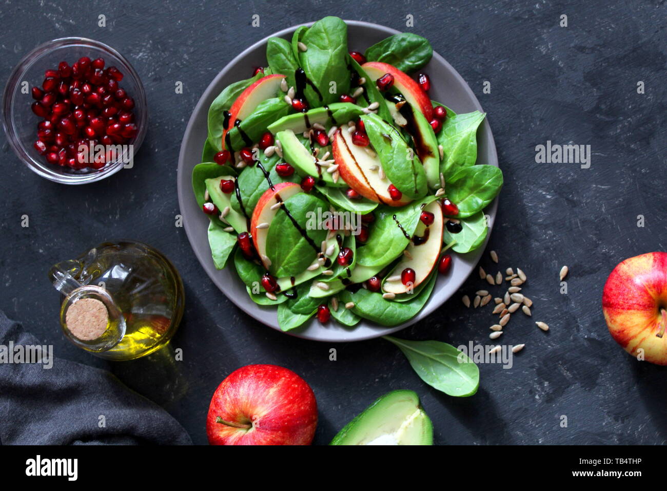 Avocat frais salade d'épinards, pommes, grenades et de tournesol sur fond sombre. Vue de dessus avec l'exemplaire de l'espace. Banque D'Images