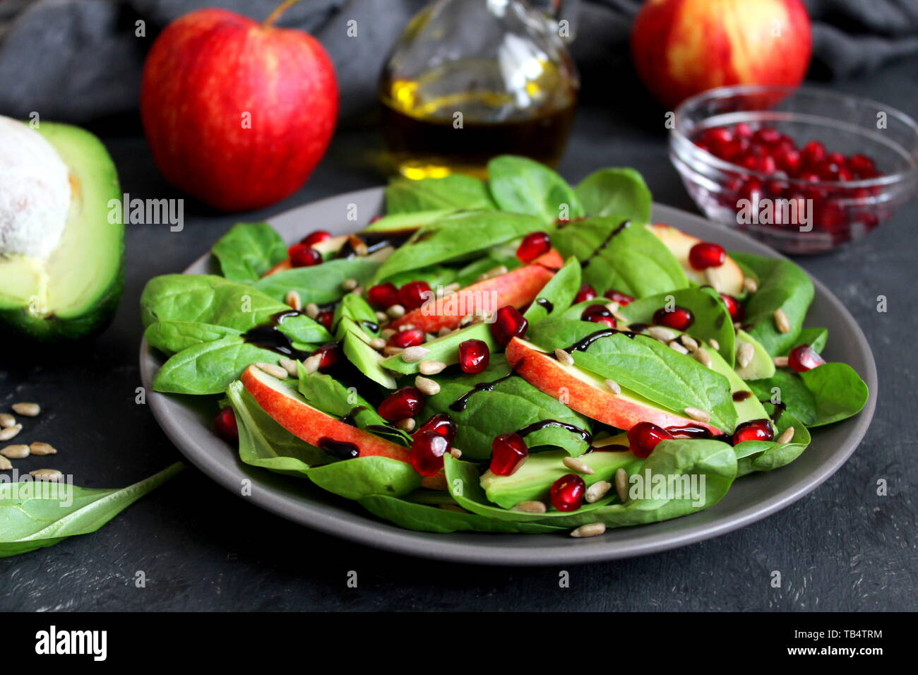 Avocat frais salade d'épinards, pommes, grenades et de tournesol sur fond sombre. Vue de dessus avec l'exemplaire de l'espace. Banque D'Images