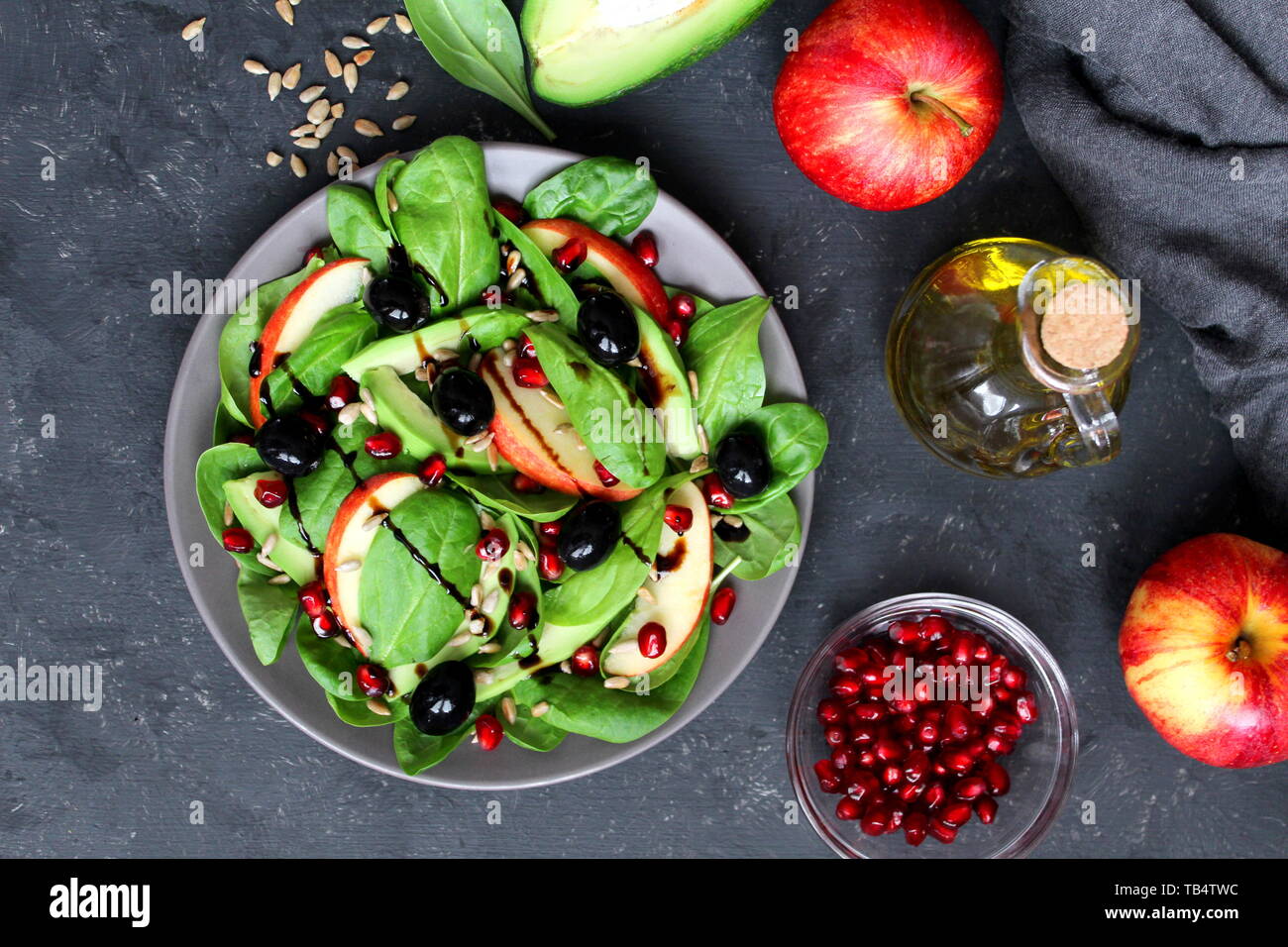 Avocat frais salade d'épinards, pommes, grenades et de tournesol sur fond sombre. Vue de dessus avec l'exemplaire de l'espace. Banque D'Images