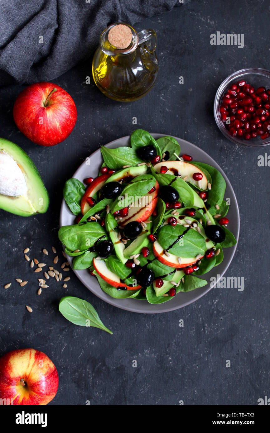 Avocat frais salade d'épinards, pommes, grenades et de tournesol sur fond sombre. Vue de dessus avec l'exemplaire de l'espace. Banque D'Images