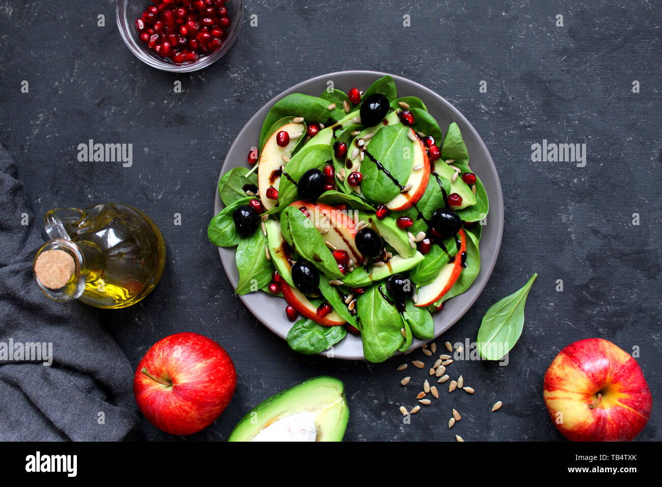 Avocat frais salade d'épinards, pommes, grenades et de tournesol sur fond sombre. Vue de dessus avec l'exemplaire de l'espace. Banque D'Images