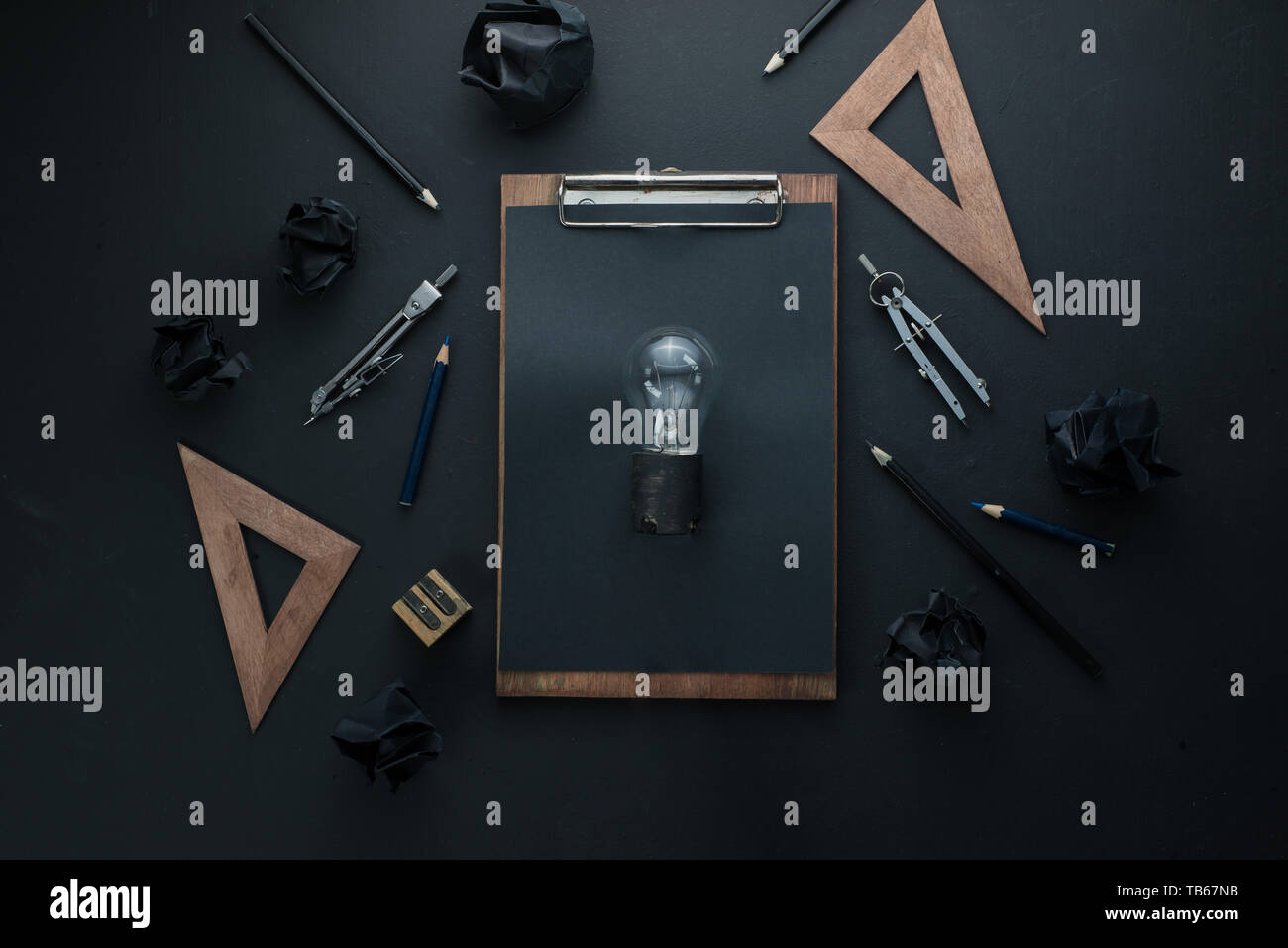 Le bâtiment et la construction, le concept d'une idée de l'ampoule sur un fond sombre avec des boussoles, des crayons, et des règles. Banque D'Images