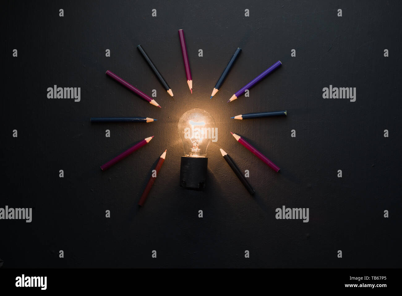 Ampoule Lumière brillant dans le noir sur noir télévision jeter avec des crayons. L'idée de l'ingénierie, la construction ou la construction concept avec copie espace. Banque D'Images