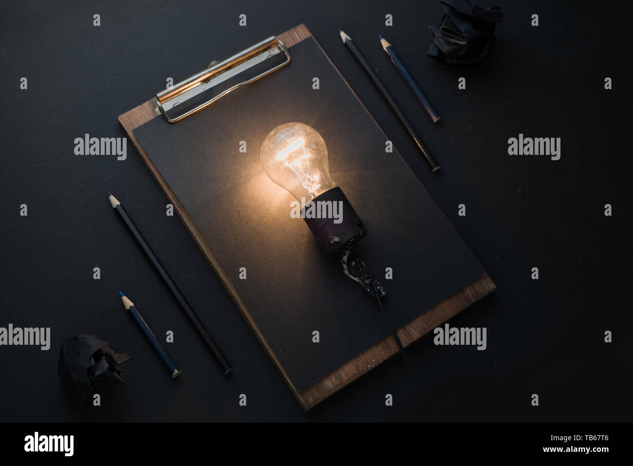 Ampoule Lumière brillant dans le noir de mise à plat avec des boules de papier froissé et un presse-papiers. L'idée de l'ingénierie, la construction ou la construction concept avec copie s Banque D'Images