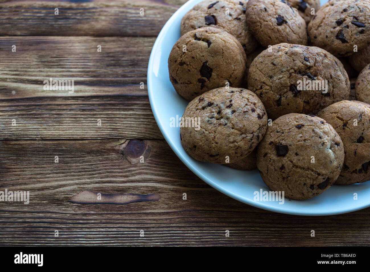 Pile de délicieux cookies aux pépites de chocolat sur une plaque sur une table en bois Banque D'Images