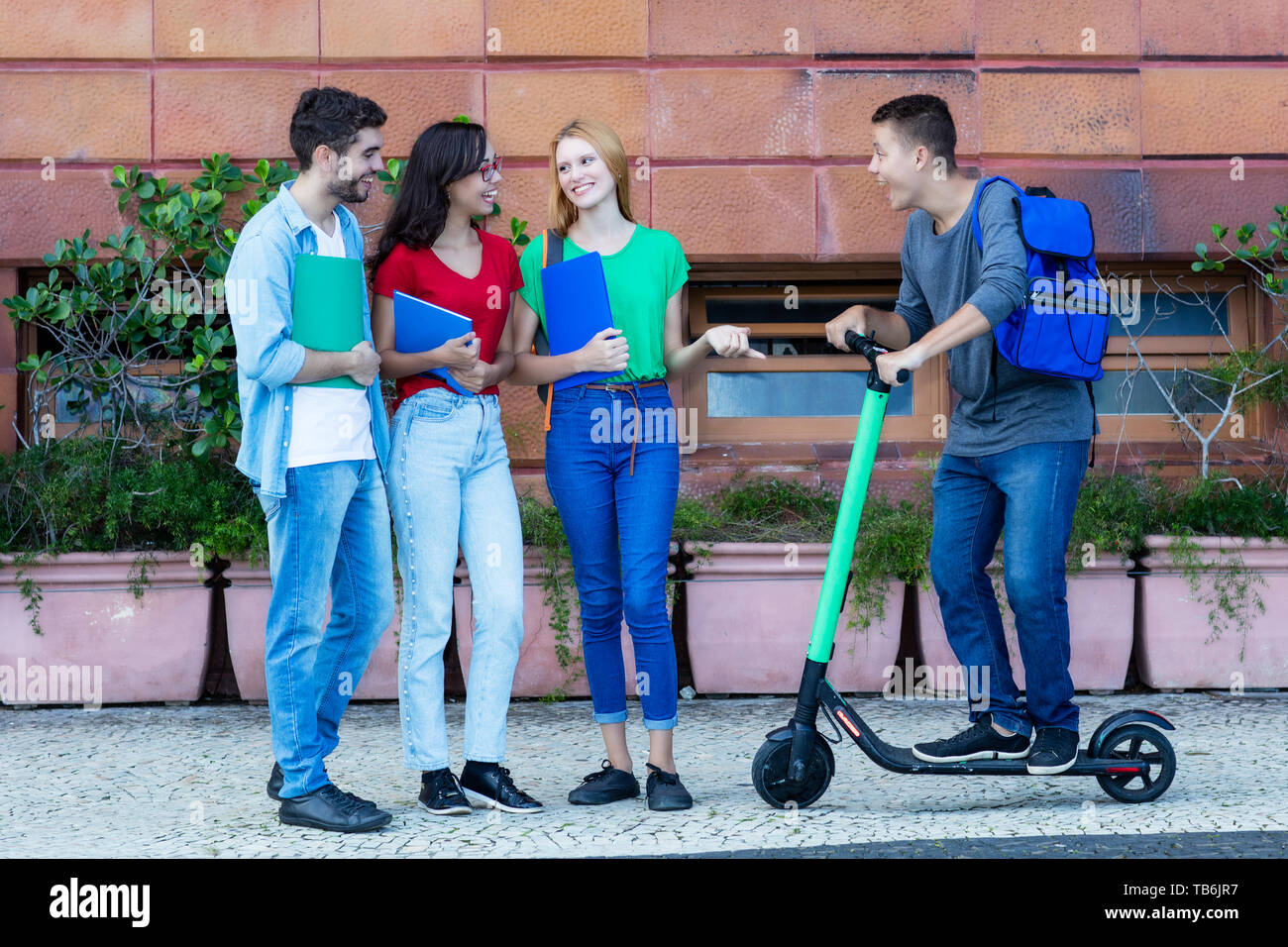 Hipster avec étudiants et amis scooter électrique dans la ville de plein air Banque D'Images