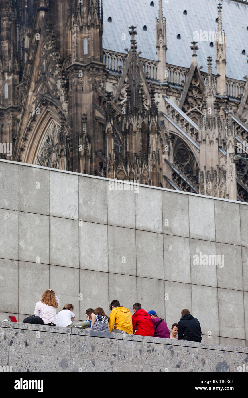 Les jeunes gens assis sur un mur au musée romain-germanique, la cathédrale, Cologne, Allemagne. Jugendliche sitzen auf einer Mauer am Roemisch-Germanis Banque D'Images