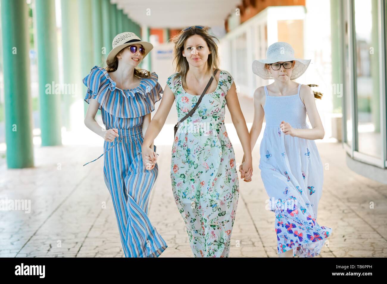 La mère et les deux filles marche main dans la main à colonnade avec piliers vert Banque D'Images