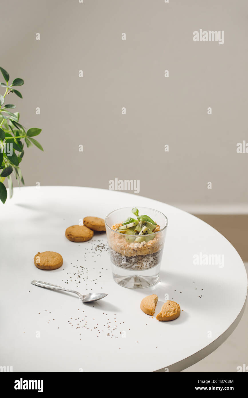 Prêt à manger sain un petit déjeuner nutritif - Granola aux amandes, graines de chia, banane et kiwi fruits et de baies et d'un bocal avec du lait à proximité Banque D'Images