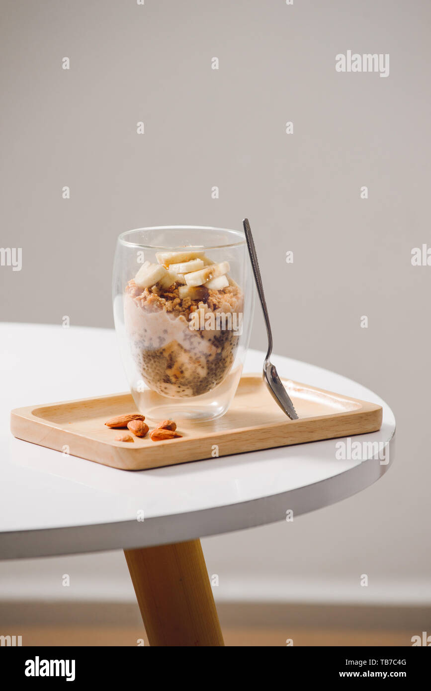 Prêt à manger sain un petit déjeuner nutritif - Granola aux amandes, graines de chia, banane et kiwi fruits et de baies et d'un bocal avec du lait à proximité Banque D'Images