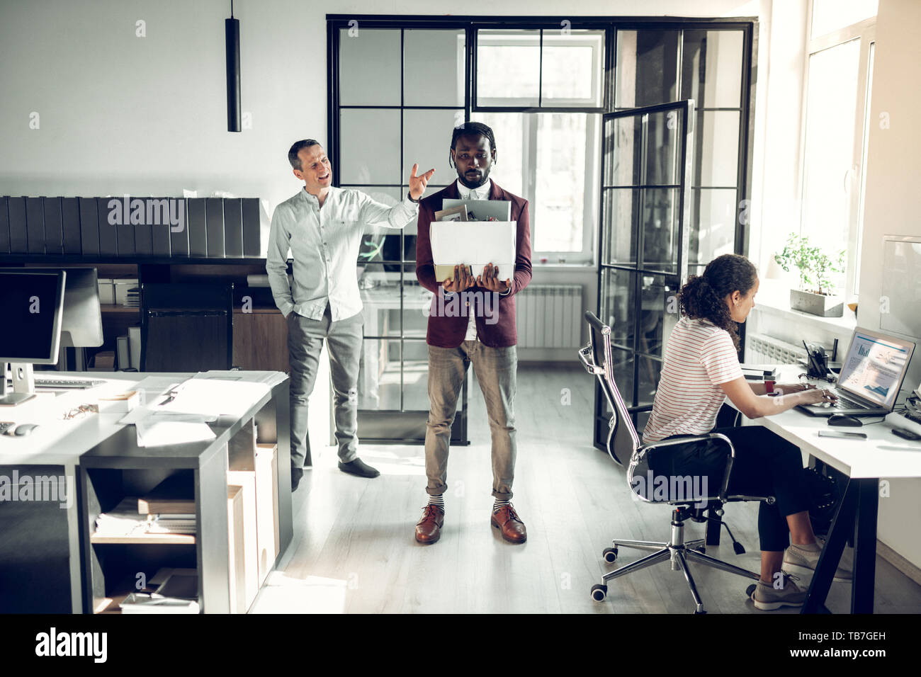 Angry boss tirant la peau sombre stagiaire après travail mensuel Banque D'Images