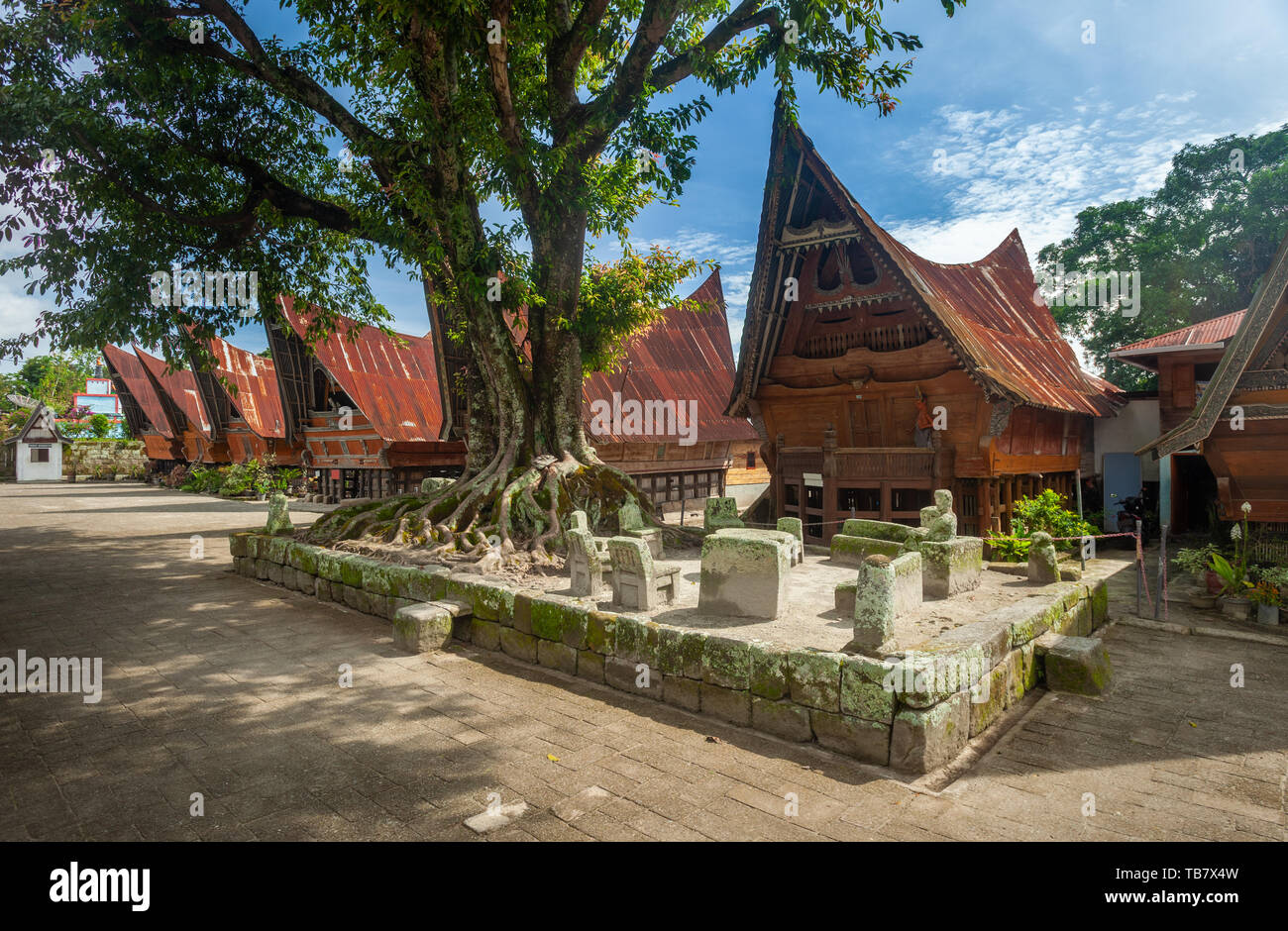 Chaises en pierre d'Ambarita et traditionnelles maisons toit Batak, île Samosir, Lac Toba Banque D'Images