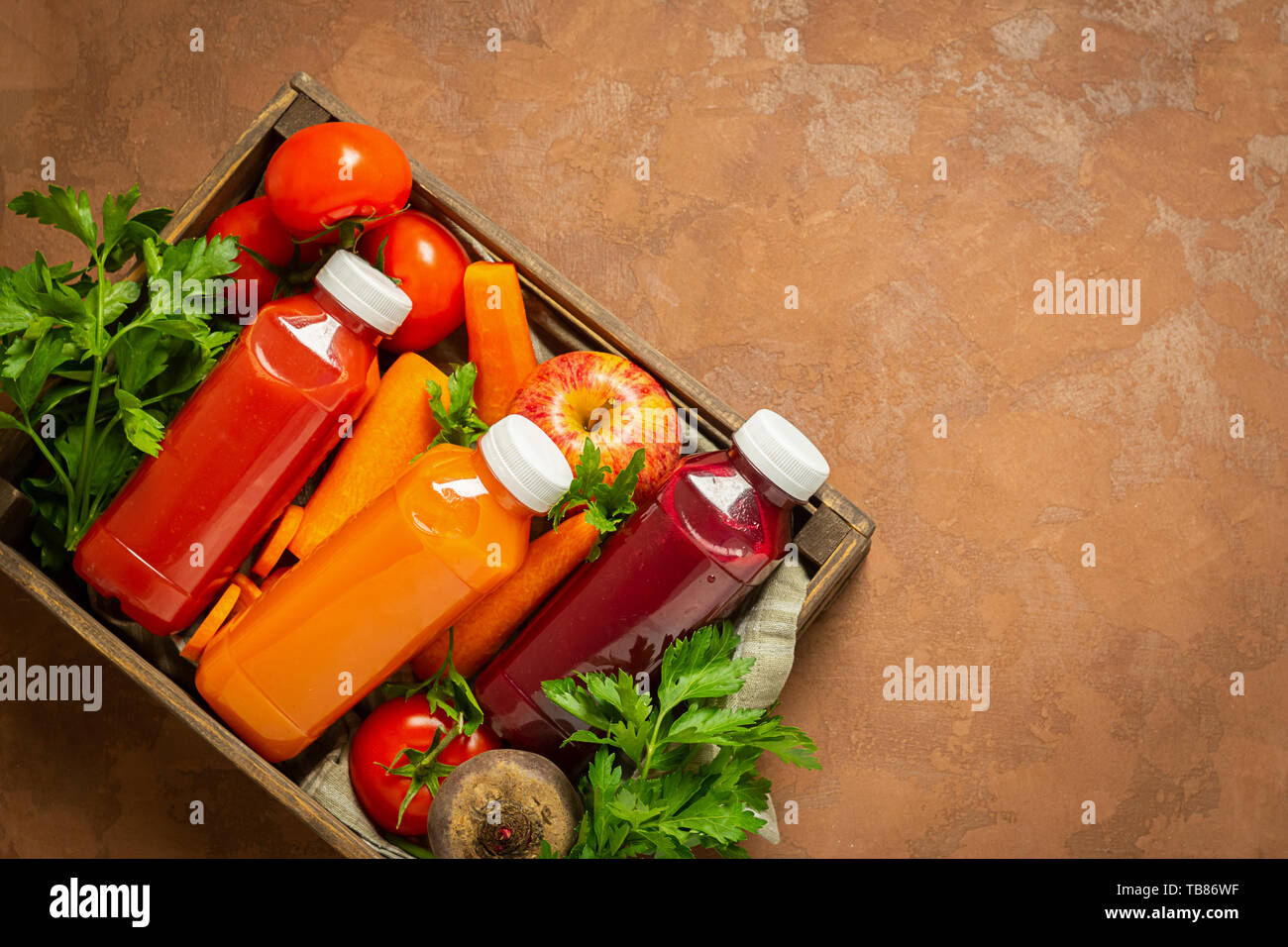 Jus de fruits frais smoothies à partir d'une variété de légumes Carottes Betteraves tomates apple en bouteilles dans une boîte en bois sur un fond brun. Vue supérieure de la télévision mise en page Banque D'Images