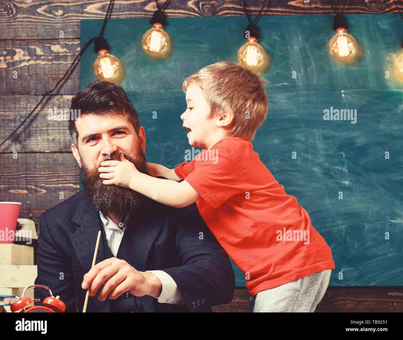 Concept de la petite enfance. Père Fils tandis que la peinture est le distraire. Petit enfant tenant la main sur la bouche de papa. Banque D'Images