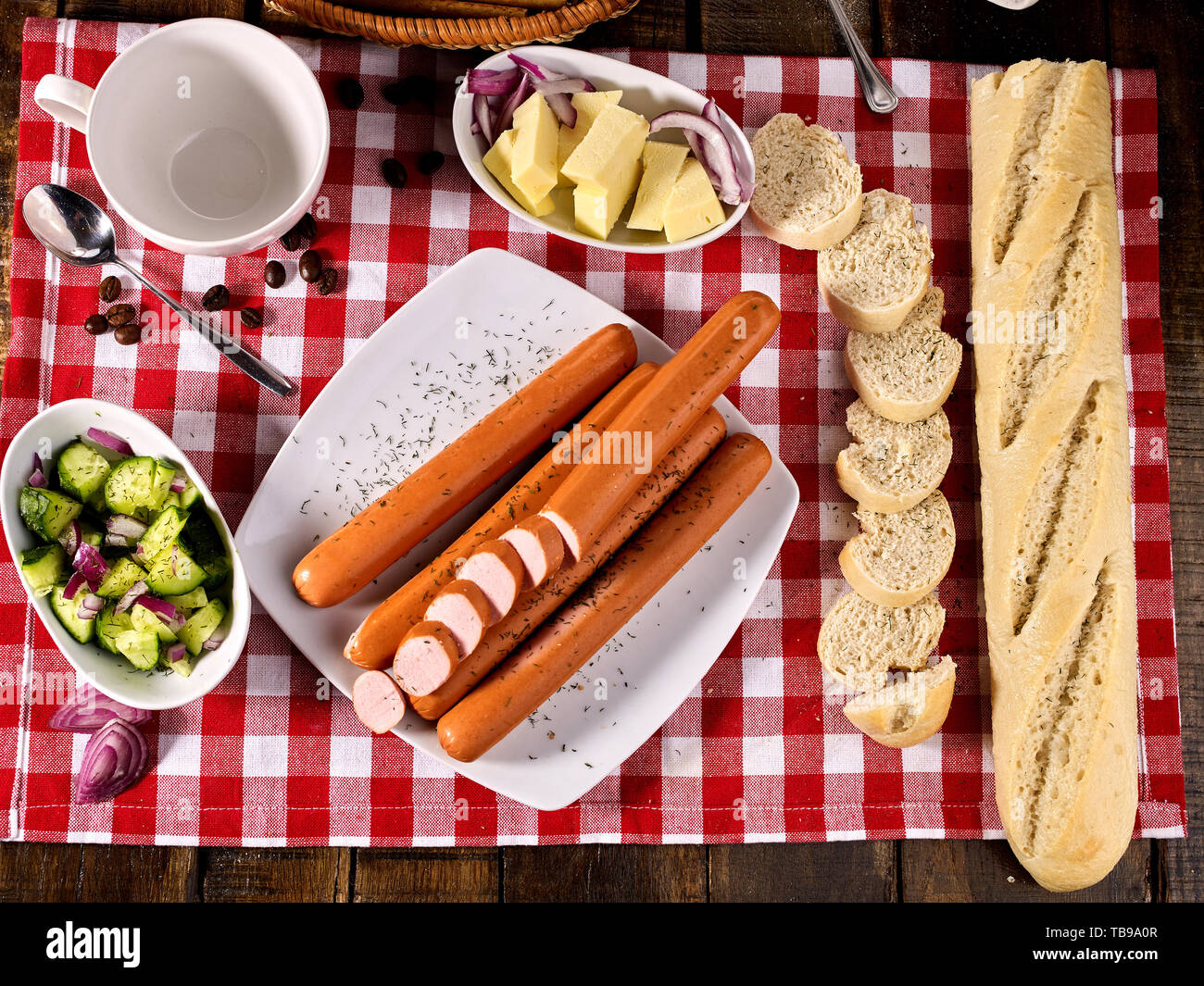Partie de la saucisse avec la baguette sur la table, sur un tissu à carreaux Banque D'Images