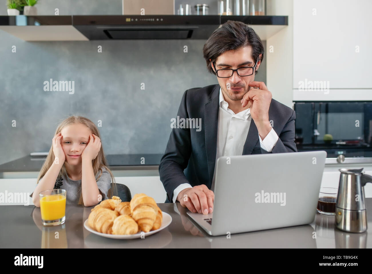 Fille ennuyé avec son père qui travaille avec un ordinateur portable Banque D'Images