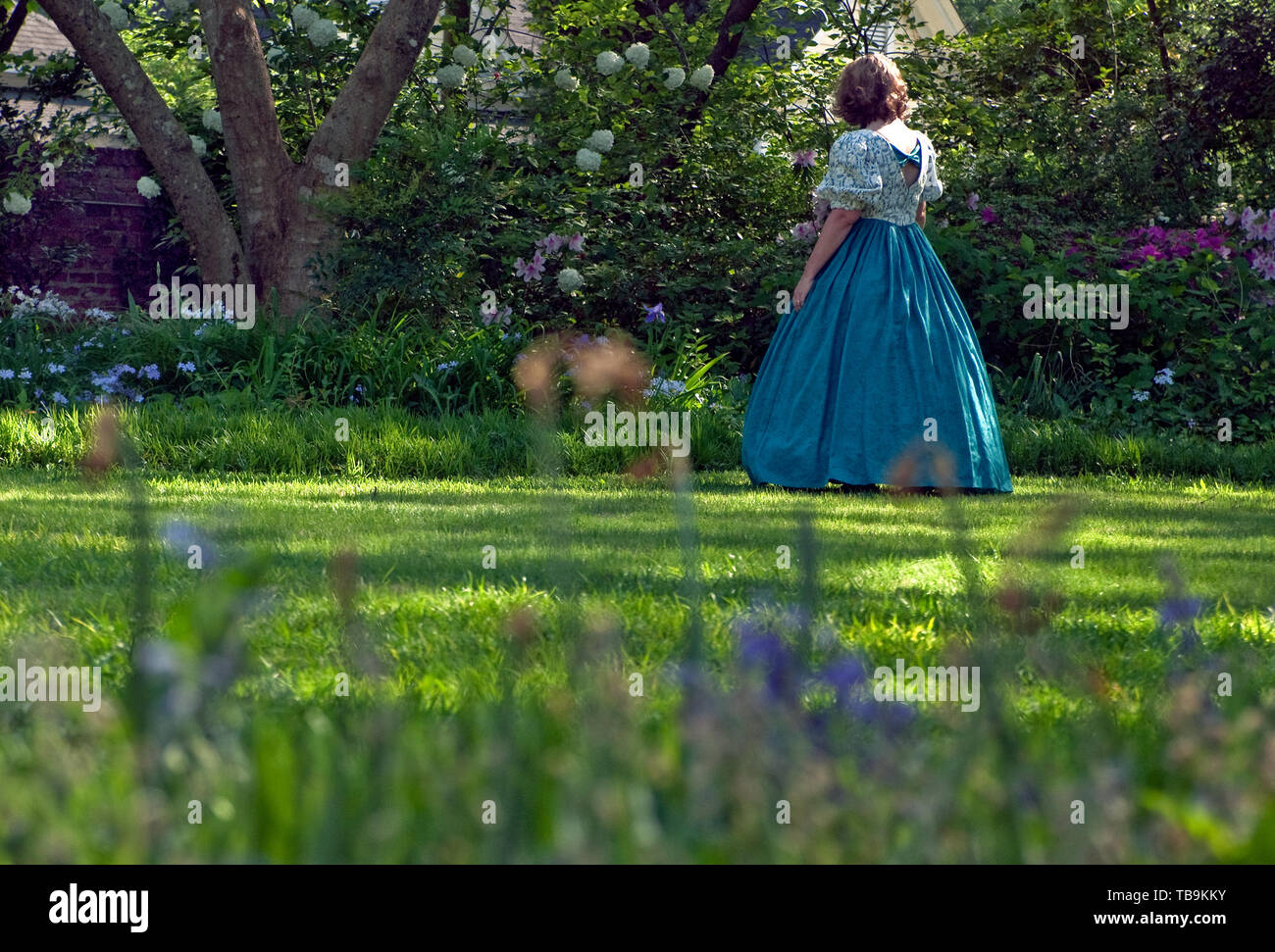 Une femme dans une robe antebellum balades à travers les jardins à colonnade, une maison historique de Columbus, Mississippi, le 17 avril 2010. Banque D'Images