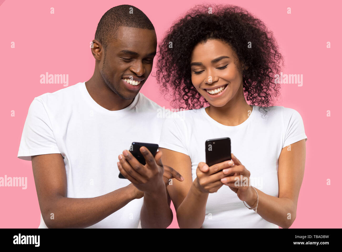 L'Afrique de l'attractive couple holding smart phones smiling s'amusant Banque D'Images