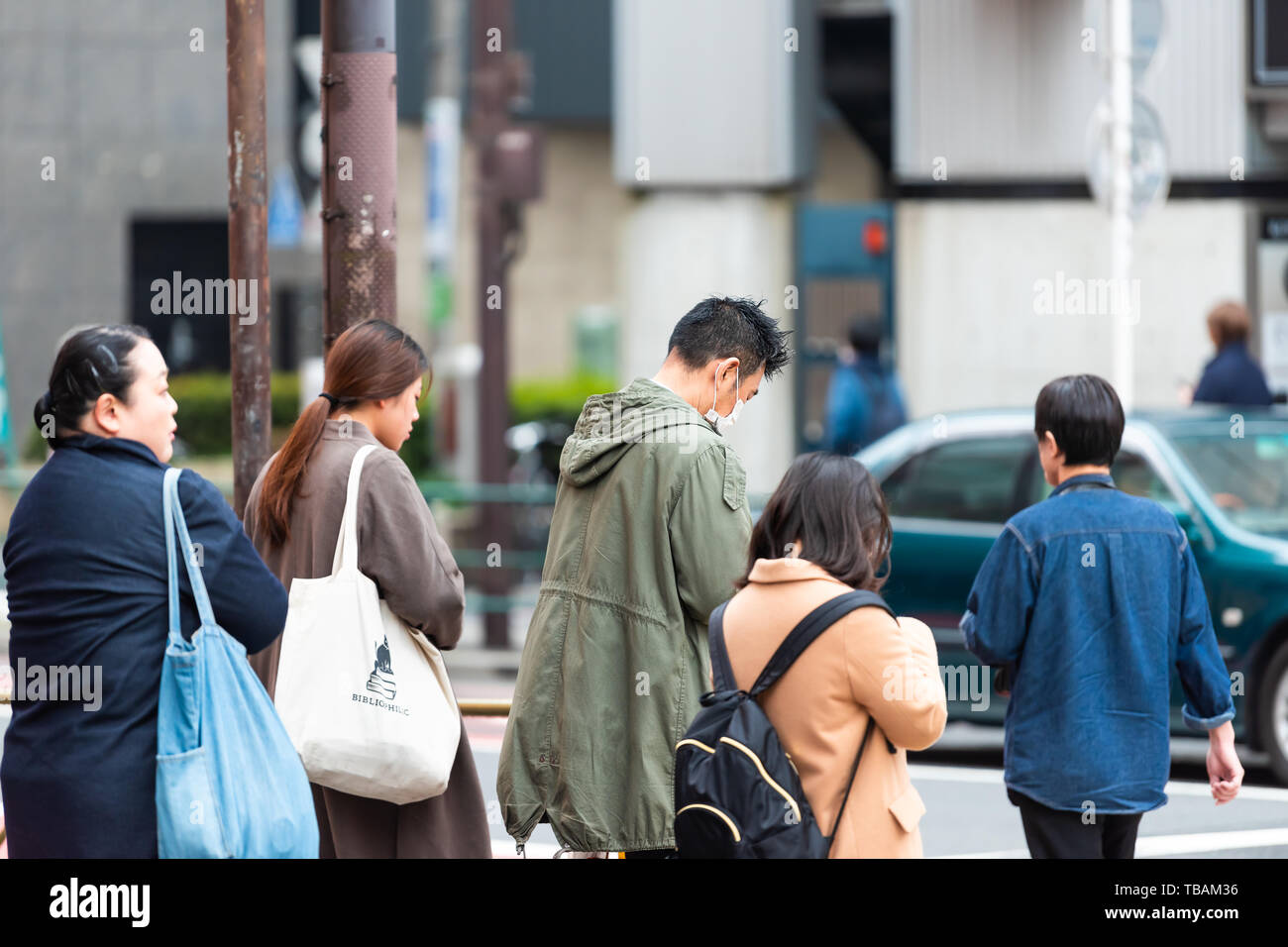 Tokyo, Japon - 30 mars 2019 : trottoir de la rue de Shinjuku avec beaucoup de gens qui attendent pour traverser la chaussée routière par bâtiment de station au cours de jour Banque D'Images