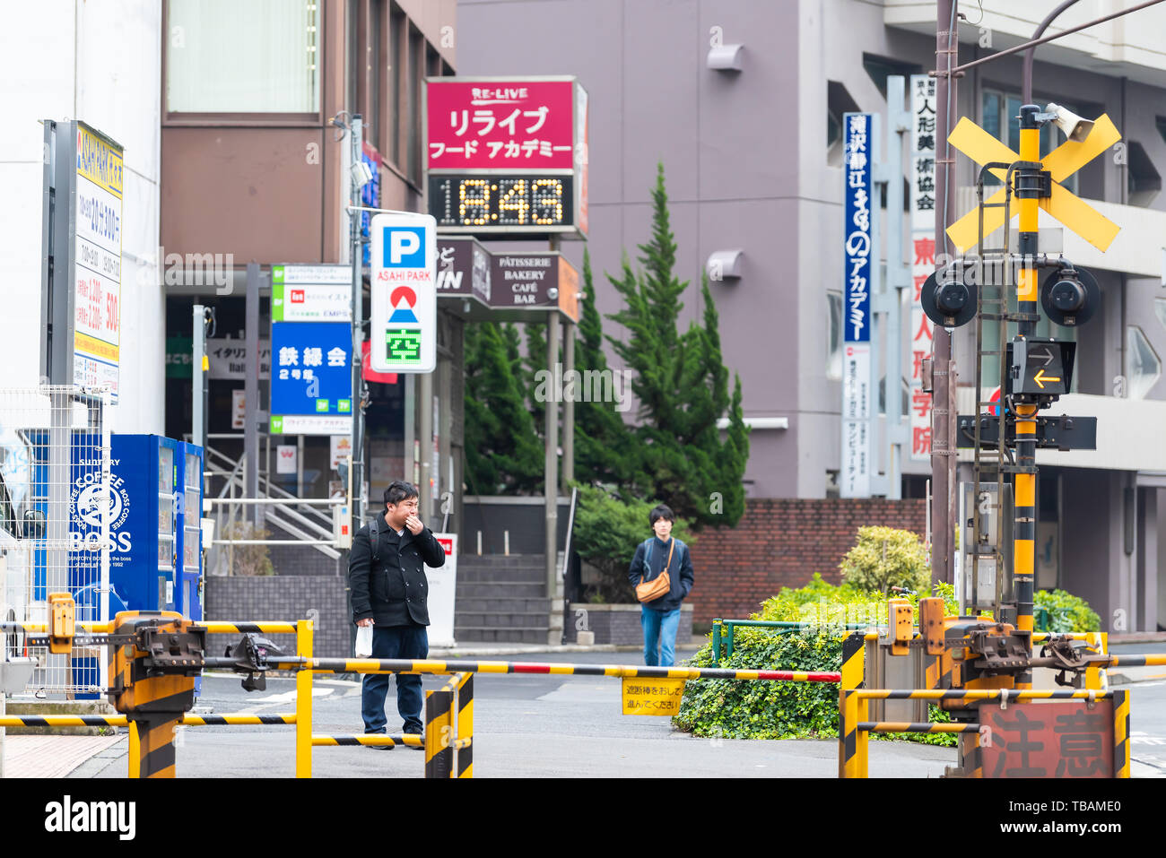 Tokyo, Japon - 30 mars 2019 : Shibuya street road par des bâtiments au cours de journée avec railroad crossing et fermé la porte et jeune homme en attente Banque D'Images