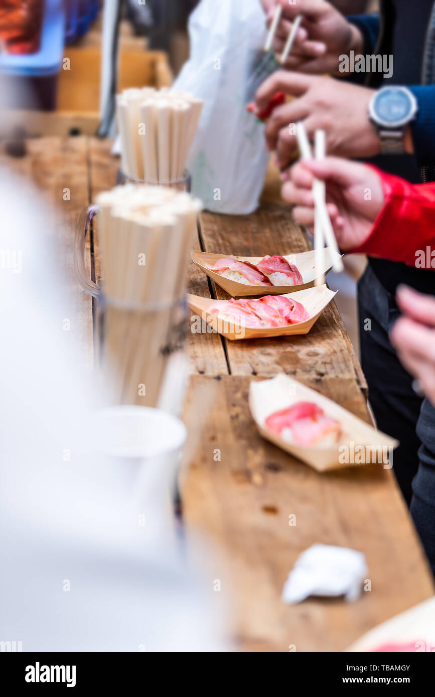 Tokyo, Japon l'Market street en gros plan avec les gens de Tsukiji sushi sashimi de manger avec des baguettes sur la table Banque D'Images