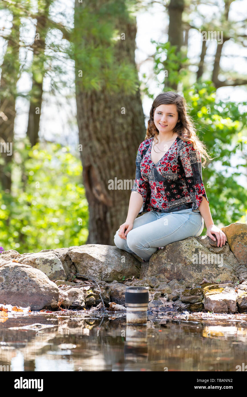 Happy woman relaxing on rocks en forêt ensoleillée au printemps à Mill Mountain park à Roanoke, Virginie par pond Banque D'Images