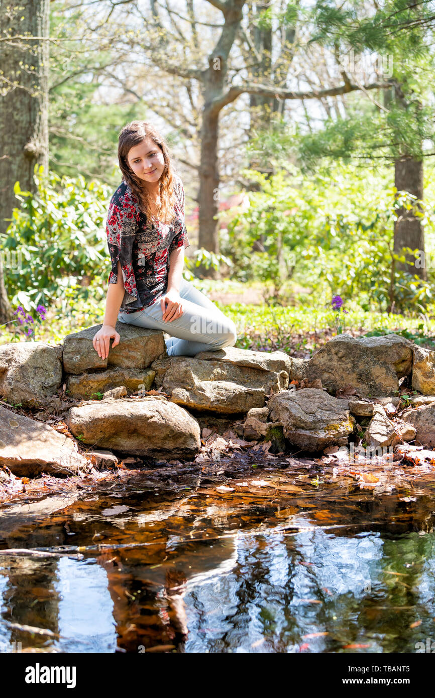 Heureux femme assise sur des rochers en forêt ensoleillée à par Mill Mountain park à Roanoke, Virginie par pond Banque D'Images