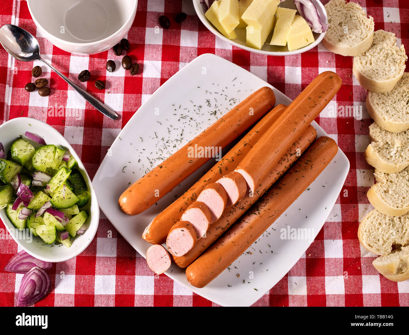 Partie de la saucisse avec la baguette sur la table, sur un tissu à carreaux Banque D'Images