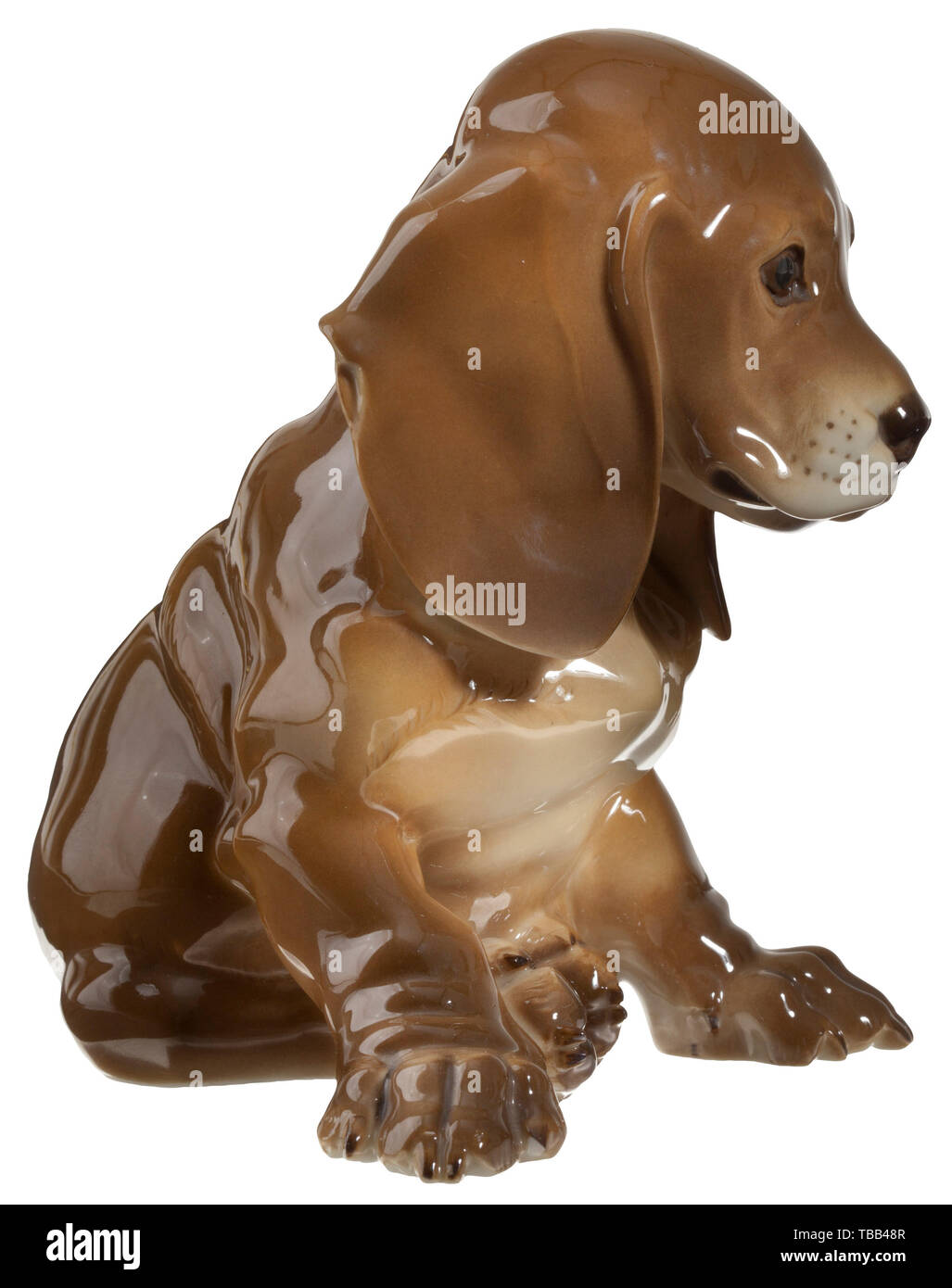 Une séance dachshund puppy en porcelaine polychrome. La partie inférieure avec la signature de l'artiste estampillé 'T. Kärner' et le numéro de modèle '2', vert underglazed fabrication's mark 'SS' Allach dans un octogone. Hauteur 14 cm. Petite puce à la griffe de l'avant-pied droit. Historique rare., historique, porcelaine, faïence, 20e siècle, Editorial-Use-seulement Banque D'Images