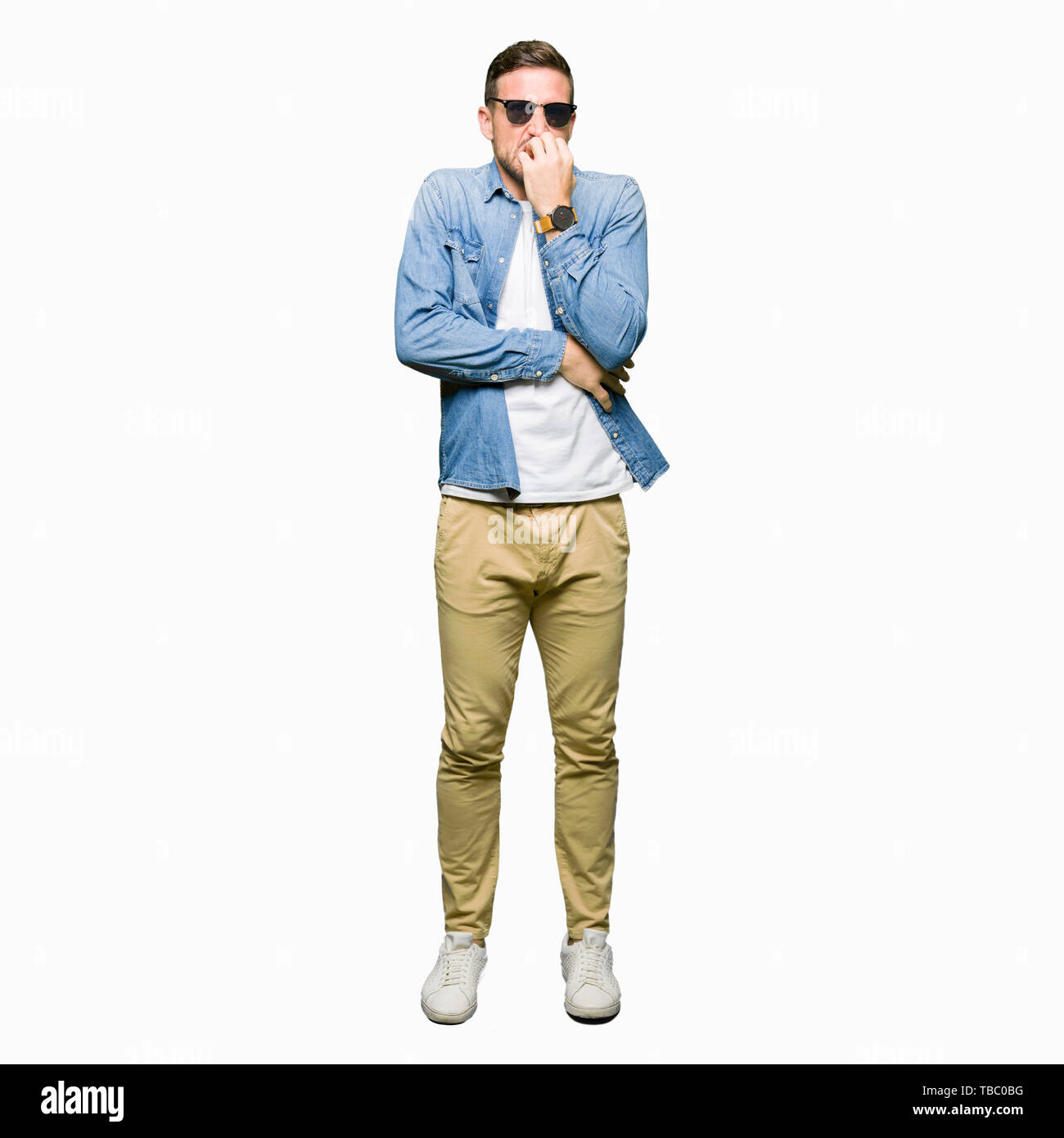 Bel homme portant des lunettes de soleil à la mode a souligné et nerveux avec les mains sur la bouche de mordre les ongles. Problème d'anxiété. Banque D'Images