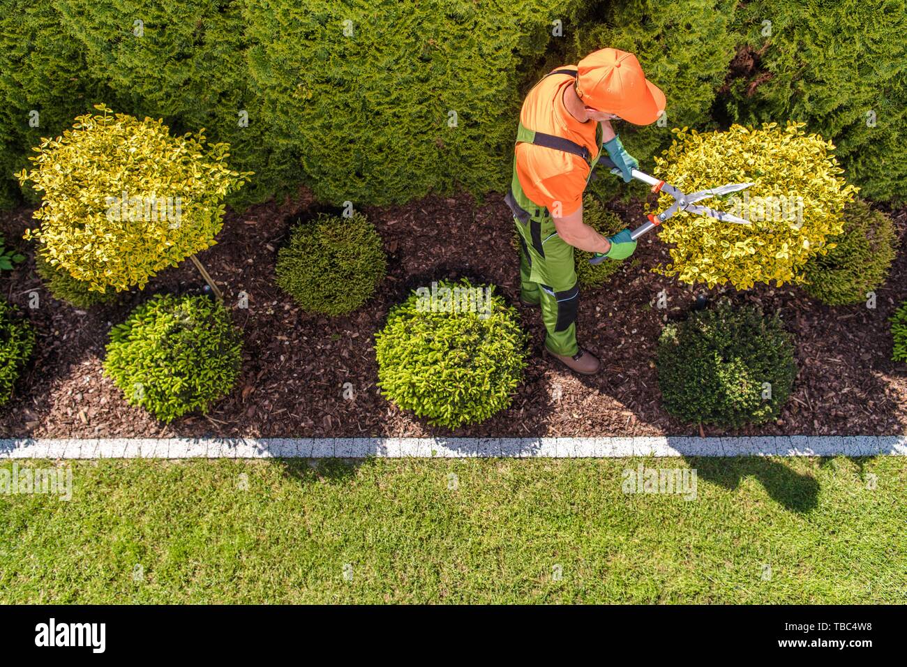 Jardinier professionnel et le grand jardin. Vue d'en haut. Printemps au moment de l'entretien. Tailler les arbres et les plantes. Banque D'Images
