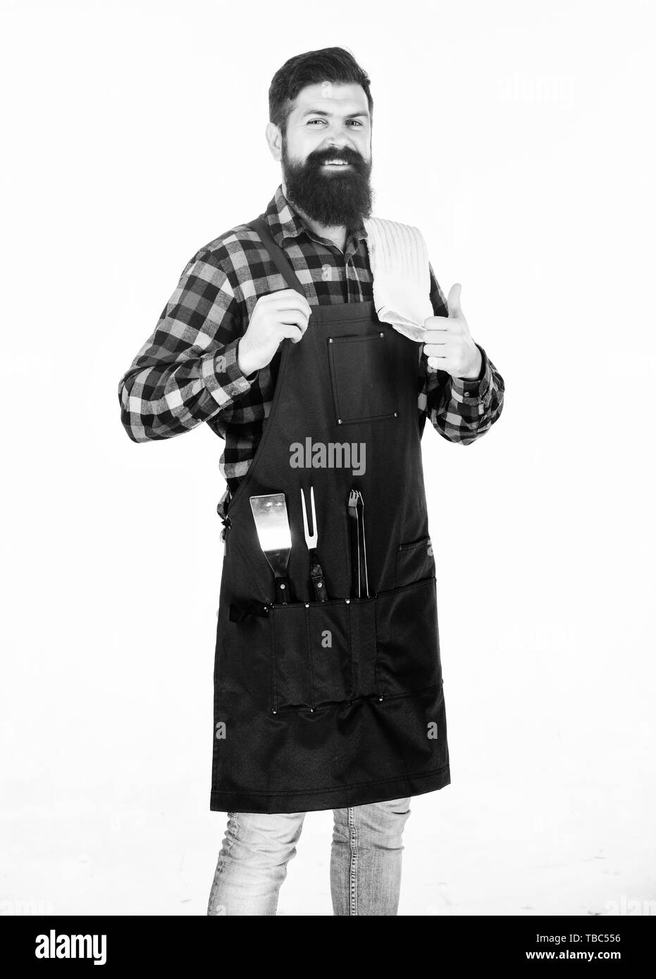 Giving Thumbs up pour son barbecue. Happy smiling cook grill barbecue au parti. Homme barbu portant un tablier barbecue avec des outils de cuisson dans des poches. Cuisiner et servir les aliments barbecue. Banque D'Images