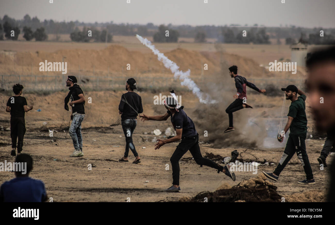 Un Palestinien renvoie une bombe de gaz lacrymogène en direction de l'armée israélienne au cours des affrontements. Les Palestiniens se sont affrontés avec les forces israéliennes au cours d'une grande manifestation sur la frontière de Gaza pour exiger le droit au retour dans leurs foyers à la frontière entre Israël et Gaza, dans le sud de la bande de Gaza. Banque D'Images