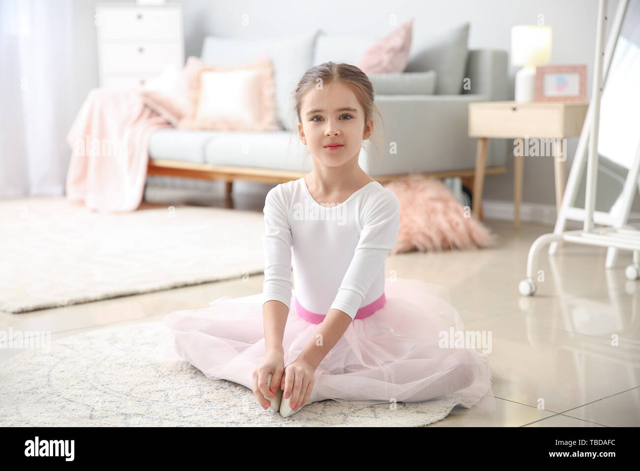 Jolie petite ballerine assis sur le plancher à la maison Photo Stock - Alamy