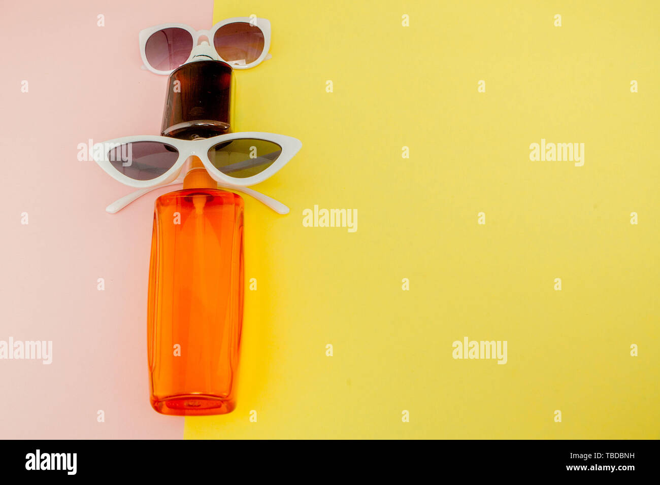 Sunblock sur bouteille carrée jaune lumineux et fond rose. Le concept de la station en mer, l'heure d'été. Haut de la vue, télévision lay, minimalisme, copy space Banque D'Images