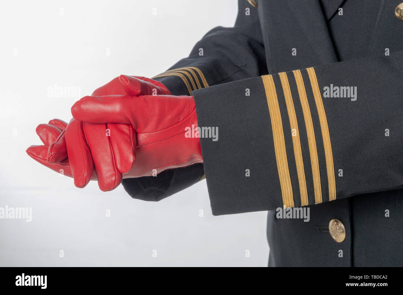 Quatre bandes d'or sur une veste uniforme avec des mains porter des gants rouges. Banque D'Images