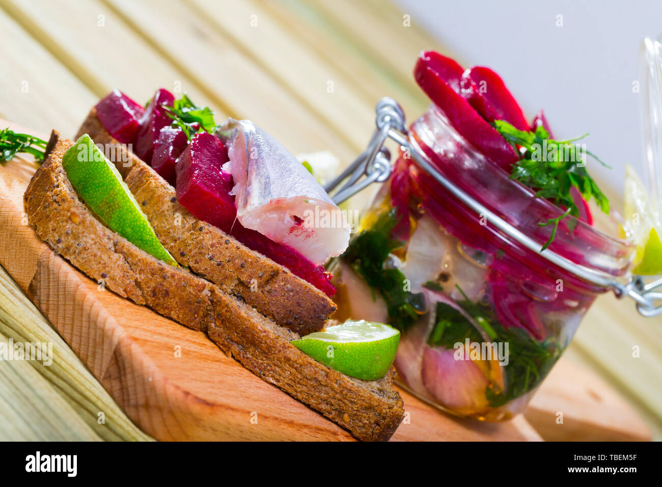 Le merlan dans la marinade au vinaigre maison d'huile d'olive et le jus de lime, de betteraves, l'oignon et les verts servi avec pain de seigle Banque D'Images