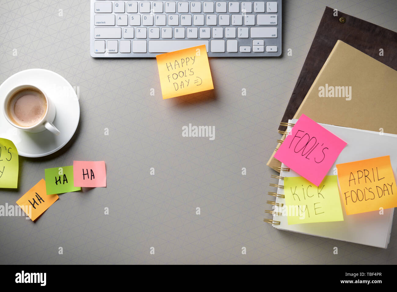 Clavier de l'ordinateur avec une tasse de café et des notes autocollantes sur fond gris. Poisson d'avril farce Banque D'Images
