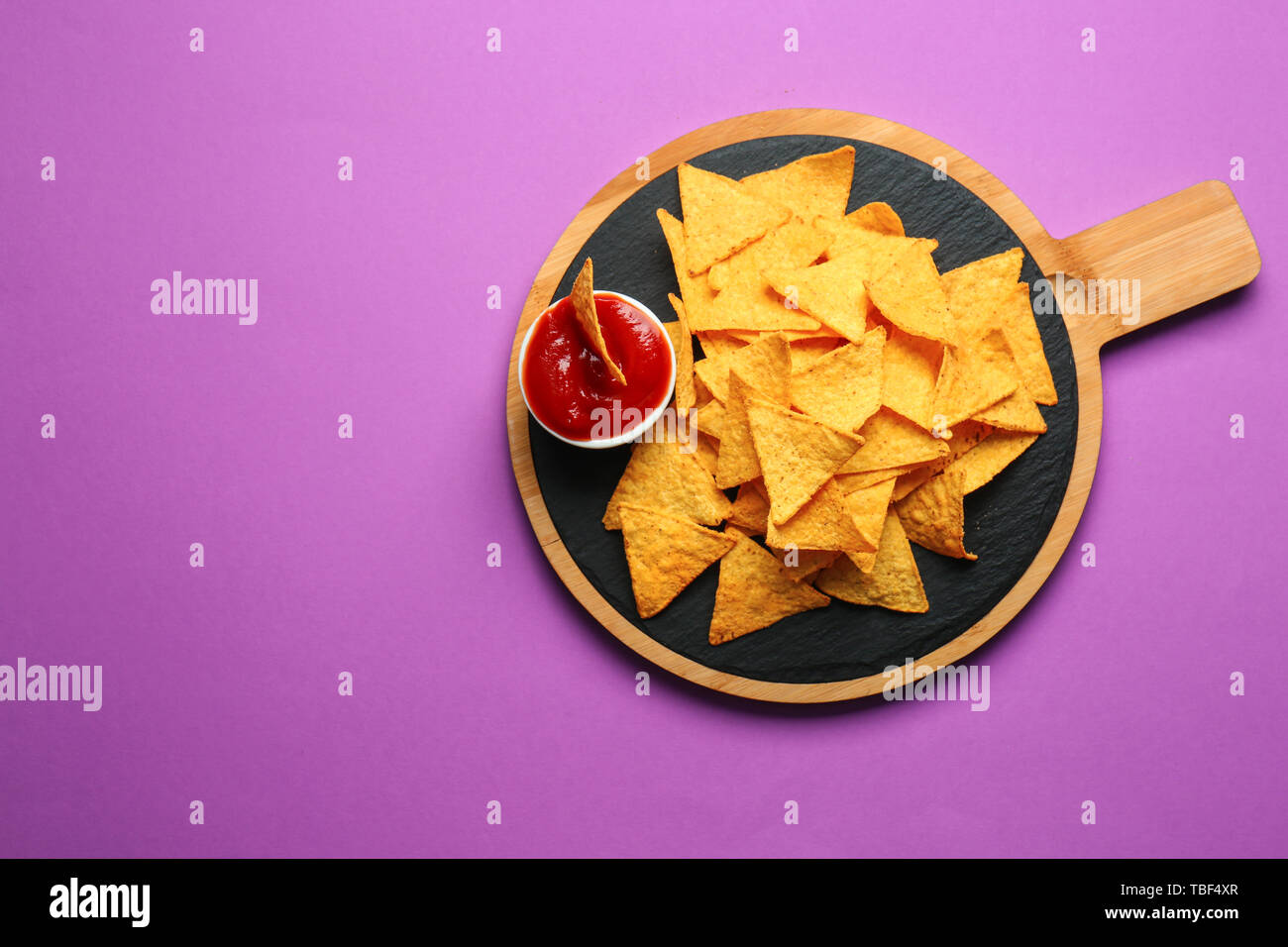 Carte avec des nachos et savoureuse sauce sur fond couleur Banque D'Images