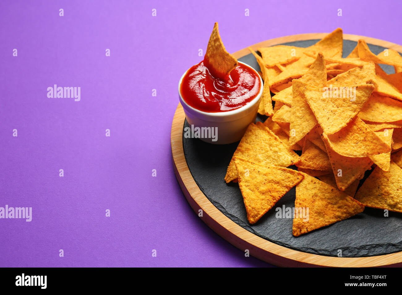 Carte avec des nachos et savoureuse sauce sur fond couleur Banque D'Images