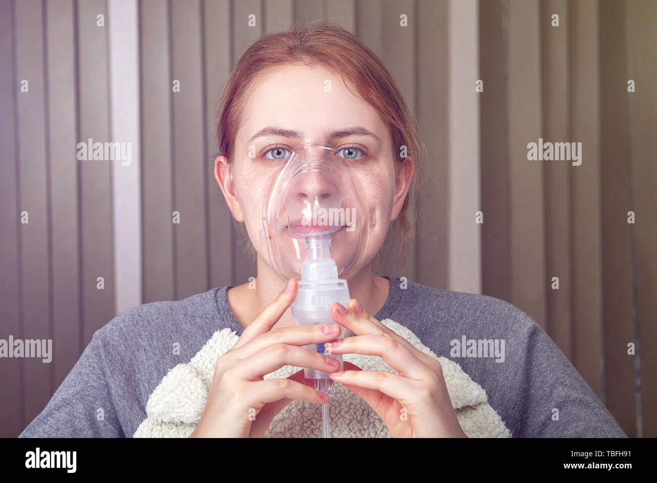 Jeune femme adulte de fibrose pulmonaire idiopathique fait inhalation avec masque nébuliseur. Banque D'Images