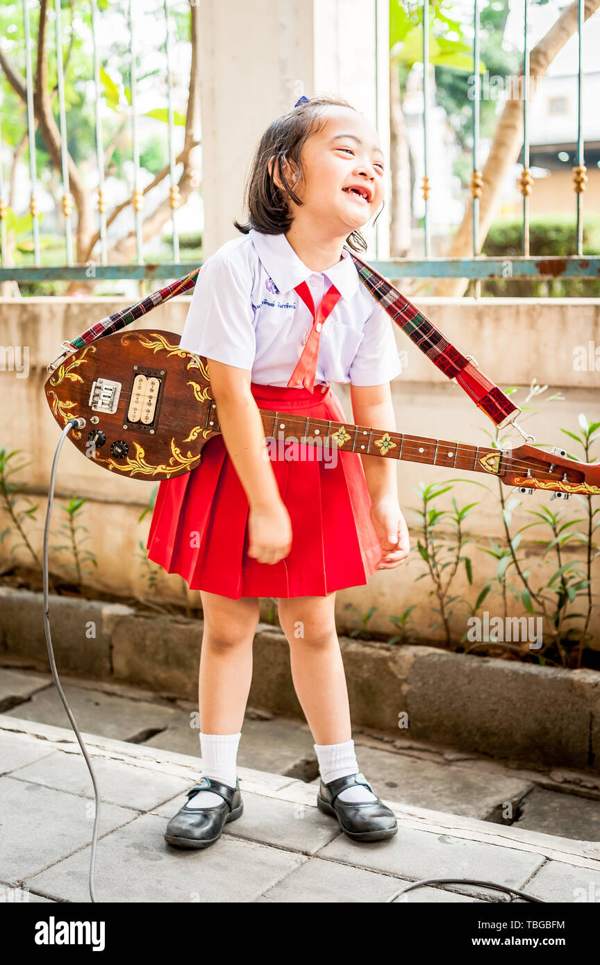 Un mignon petit Thai girl effectue au public en jouant de sa guitare à Bangkok en Thaïlande. Banque D'Images