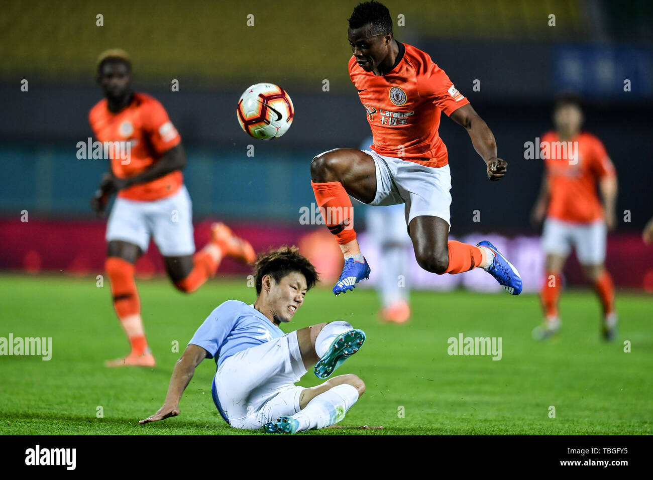 Joueur de football Kenyan Ayub Masika, haut, de Pékin Renhe passe le ballon contre un joueur de Tianjin Tianhai dans leur 12e match au cours de l'Association de football chinoise 2019 Super League (CSL), à Beijing, Chine, 1 juin 2019. Renhe Beijing Tianjin Tianhai défait 2-0. Banque D'Images