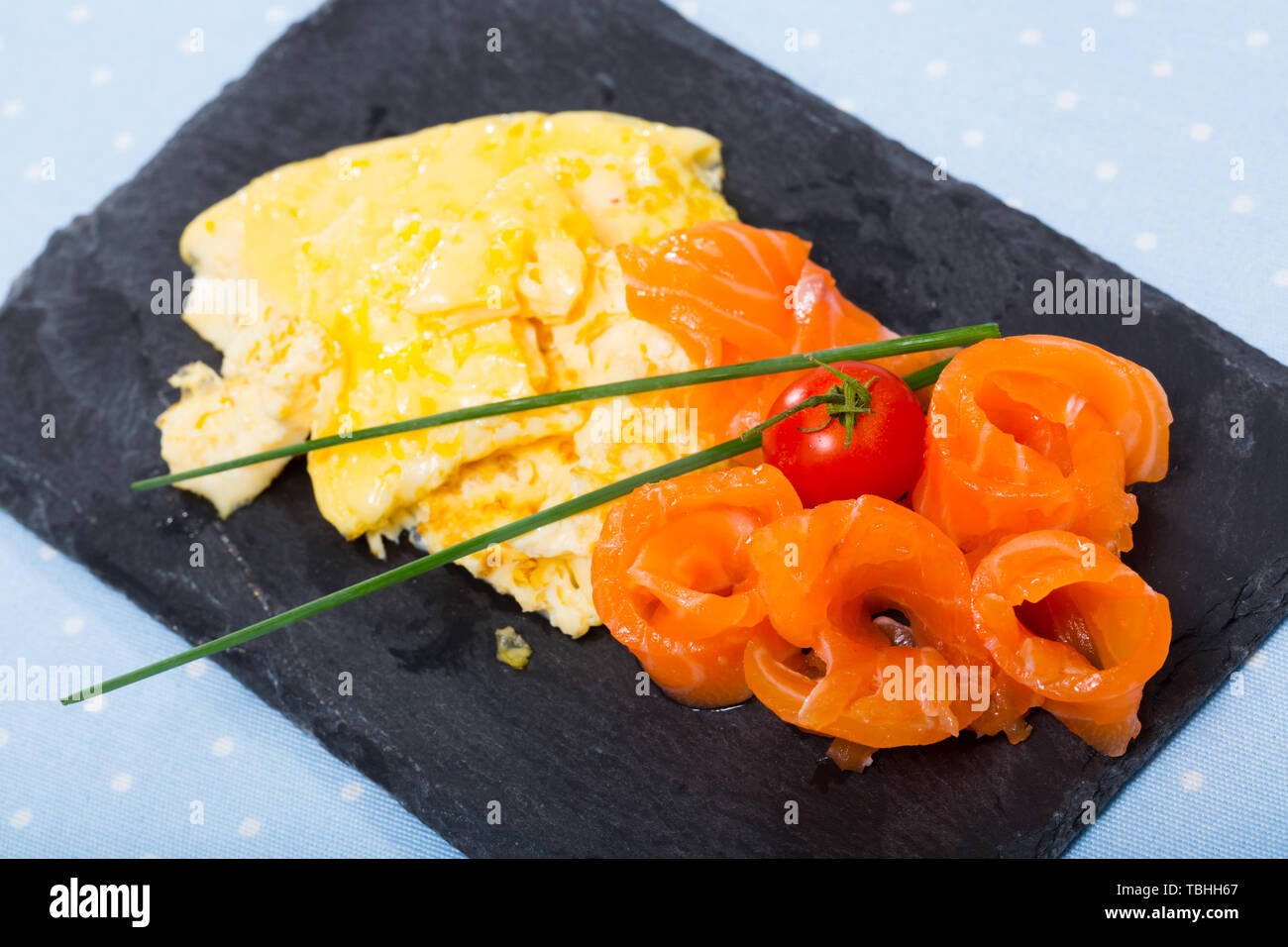 Omelette délicieux avec le saumon fumé, l'oignon vert et les tomates servi sur tableau noir Banque D'Images