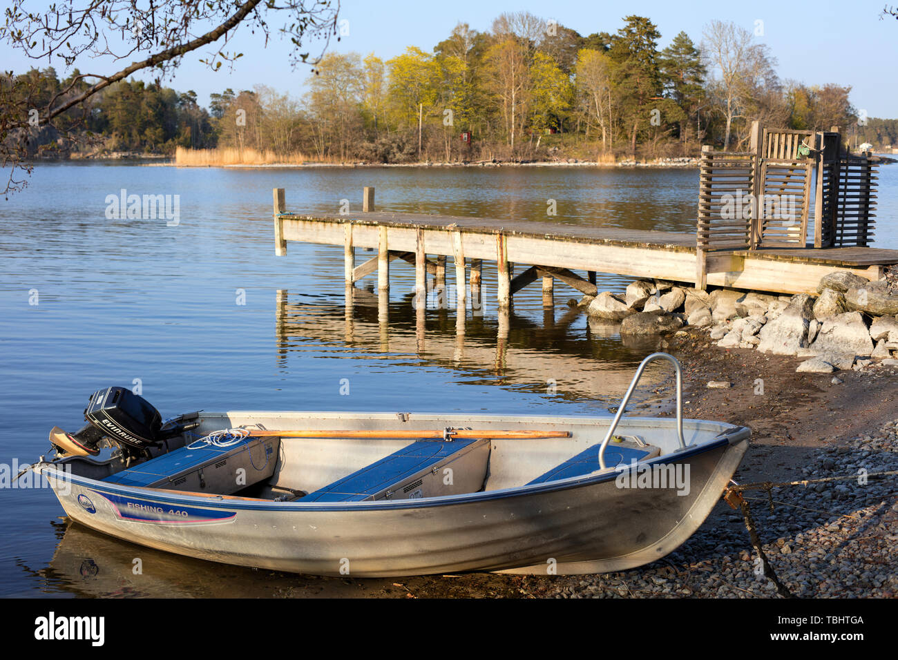 Bateau en aluminium à côté d'une jetée en bois à Styrmansholmen, Karlsudd, près de Vaxholm, en Suède, en fin d'après-midi de printemps Banque D'Images