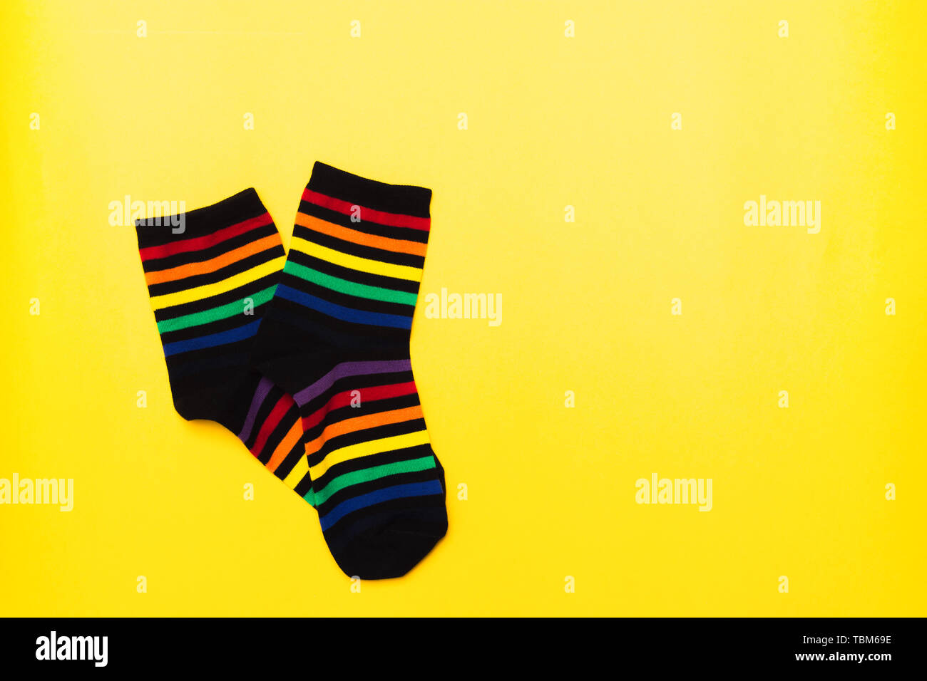 Textile chaussettes en coton noir avec motif à rayures colorées lumineuses sur fond jaune avec copie espace Banque D'Images