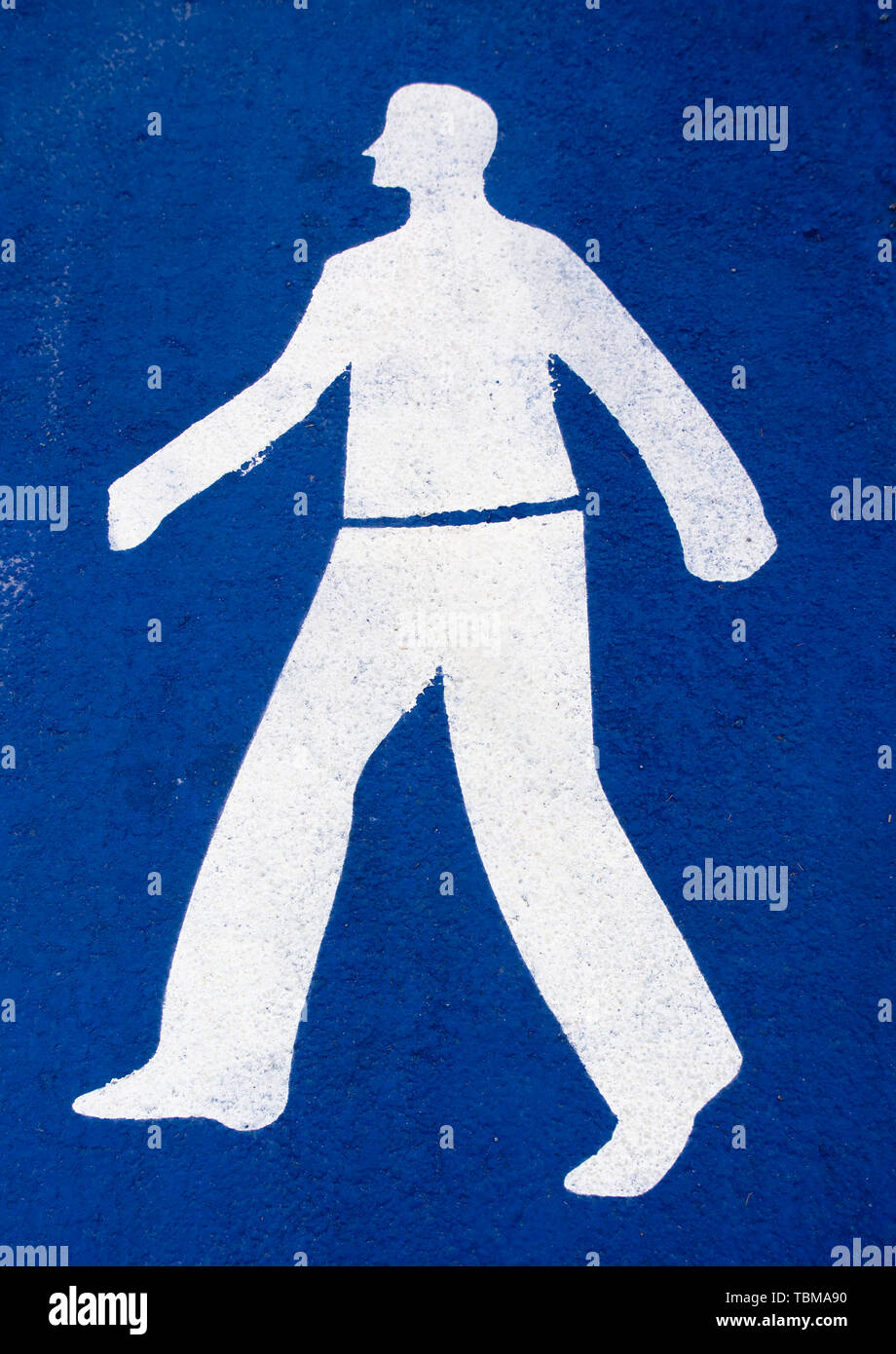 La figure de l'homme blanc sur fond bleu, signe peint sur l'asphalte, l'île de Tinos, Grèce port. Banque D'Images